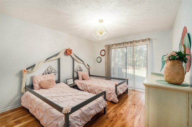 bedroom featuring light wood-type flooring, a textured ceiling, and an inviting chandelier