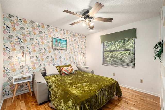 bedroom with a textured ceiling, light wood-type flooring, and ceiling fan