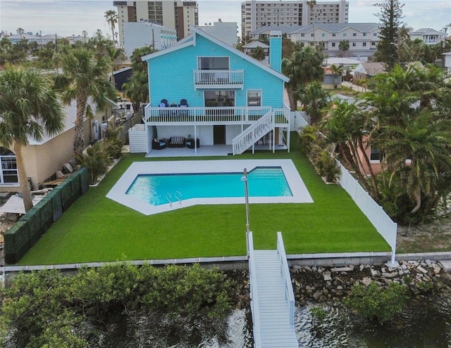 back of house featuring a patio area, a fenced in pool, a yard, and a balcony