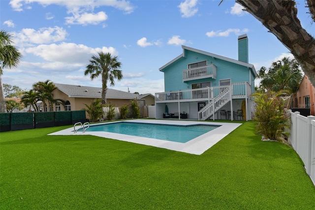 rear view of property featuring a yard, a fenced in pool, a patio, and a balcony