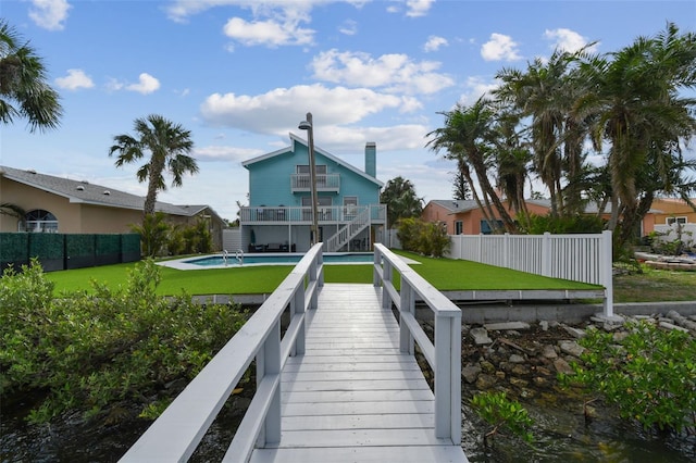 rear view of property featuring a balcony and a lawn