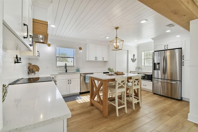 kitchen with white cabinetry, sink, light hardwood / wood-style flooring, decorative light fixtures, and appliances with stainless steel finishes