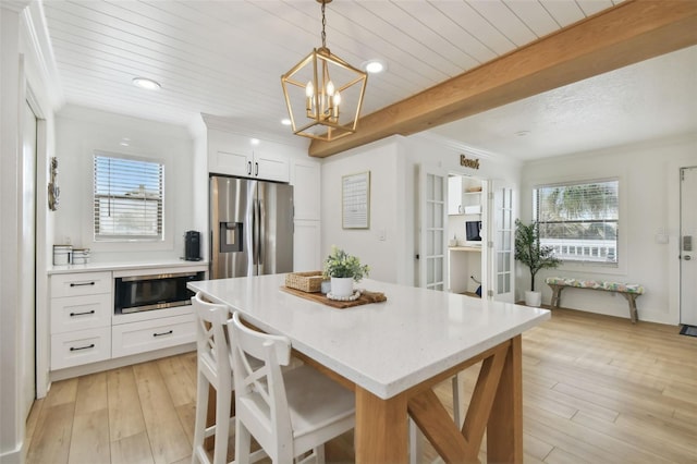 kitchen with appliances with stainless steel finishes, decorative light fixtures, white cabinetry, and plenty of natural light