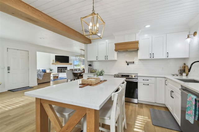 kitchen with stainless steel appliances, white cabinetry, sink, and light hardwood / wood-style flooring