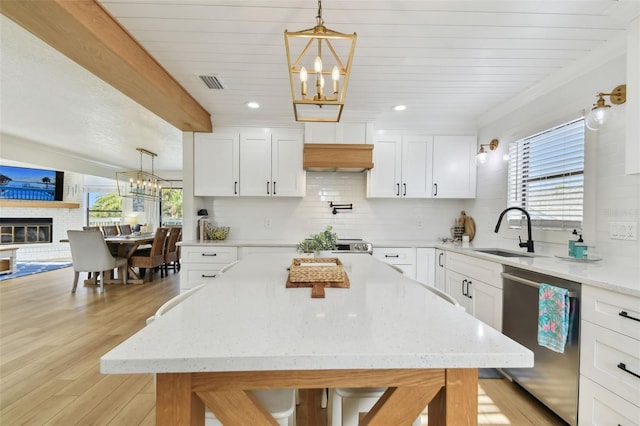 kitchen featuring a brick fireplace, dishwasher, white cabinets, and light hardwood / wood-style flooring