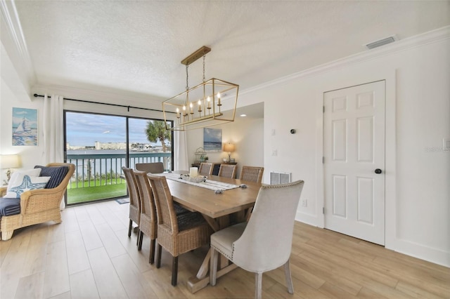 dining space featuring crown molding, a water view, and light wood-type flooring