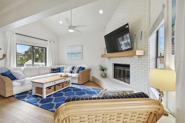 living room with ceiling fan, a brick fireplace, lofted ceiling, hardwood / wood-style flooring, and ornamental molding