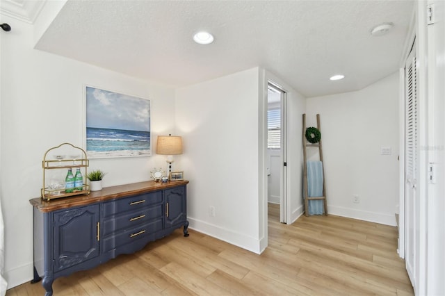 hall featuring a textured ceiling and light hardwood / wood-style floors