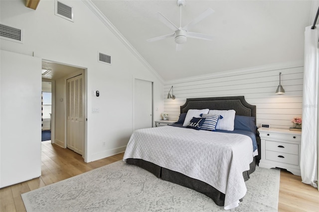 bedroom with wood walls, high vaulted ceiling, crown molding, ceiling fan, and light hardwood / wood-style floors