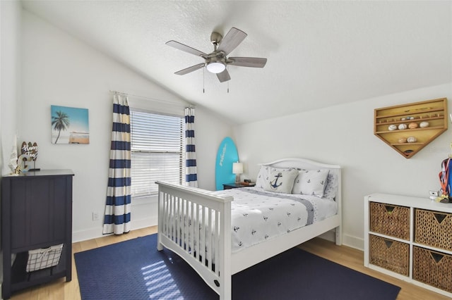 bedroom with hardwood / wood-style flooring, ceiling fan, lofted ceiling, and a textured ceiling