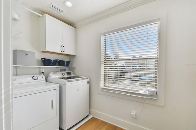 washroom featuring cabinets, light wood-type flooring, separate washer and dryer, and ornamental molding