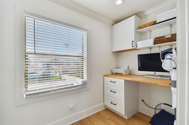 office with a textured ceiling, built in desk, light hardwood / wood-style floors, and ornamental molding