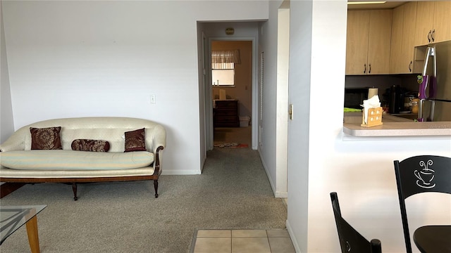 kitchen with light carpet, stainless steel fridge, and light brown cabinetry