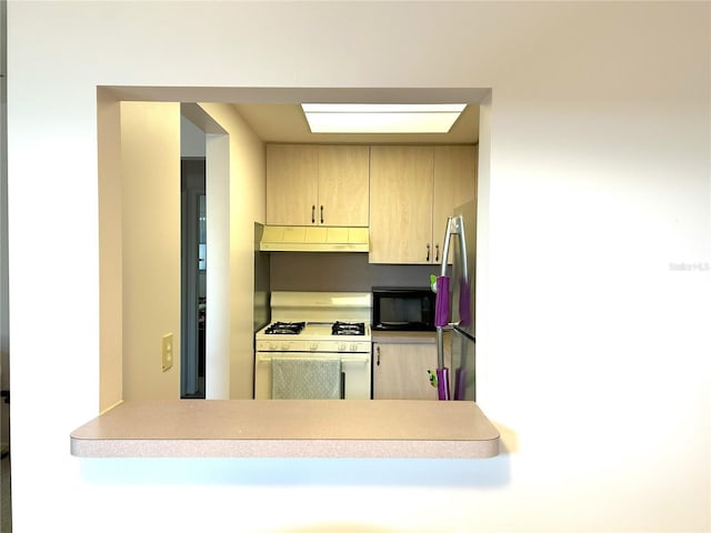 kitchen with kitchen peninsula, stainless steel fridge, light brown cabinets, and white range with gas stovetop