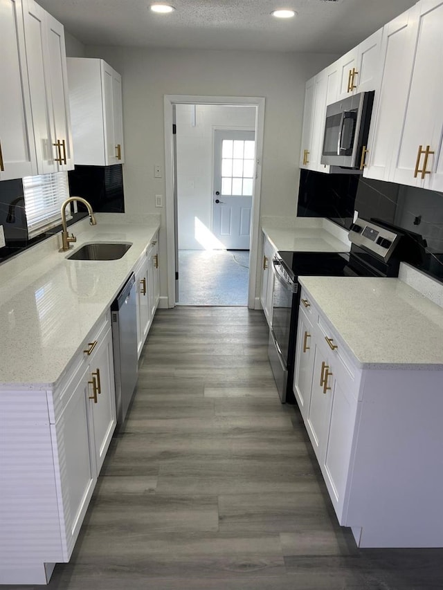 kitchen featuring white cabinets, sink, light stone countertops, appliances with stainless steel finishes, and dark hardwood / wood-style flooring