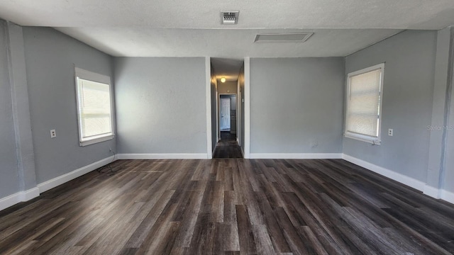 unfurnished room featuring dark hardwood / wood-style flooring and a textured ceiling