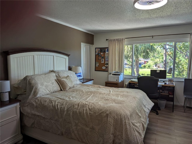 bedroom featuring a textured ceiling, light hardwood / wood-style floors, and crown molding