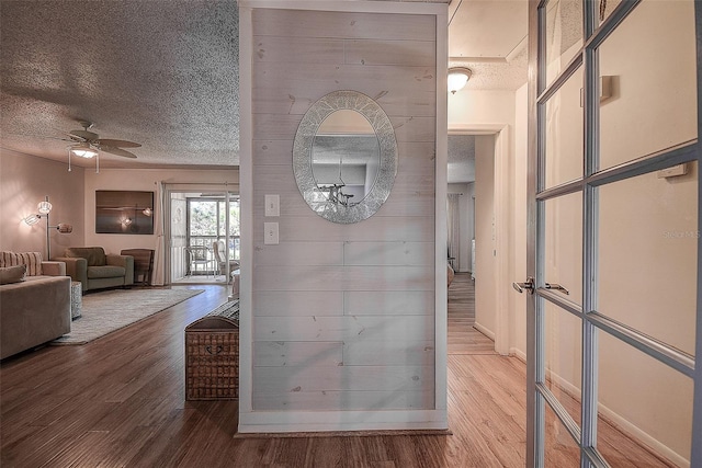 interior space featuring a chandelier, a textured ceiling, hardwood / wood-style flooring, and wooden walls