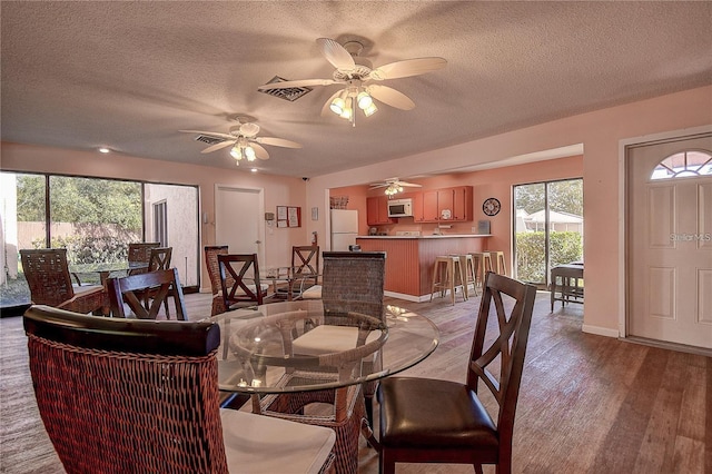 dining space featuring ceiling fan, a textured ceiling, and light hardwood / wood-style flooring