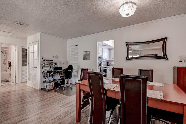 dining room with a textured ceiling and light hardwood / wood-style flooring