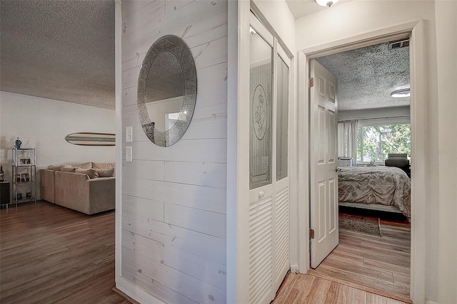 corridor featuring a textured ceiling and hardwood / wood-style flooring