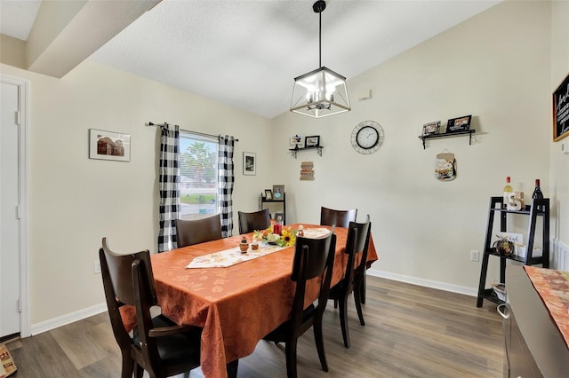 dining space with a chandelier, dark wood-type flooring, and vaulted ceiling