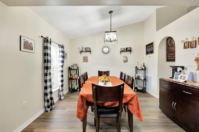 dining room with a chandelier, light hardwood / wood-style floors, and vaulted ceiling