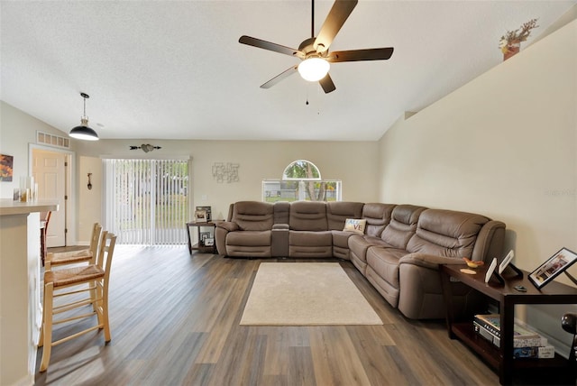 living room with ceiling fan, dark hardwood / wood-style flooring, lofted ceiling, and a textured ceiling