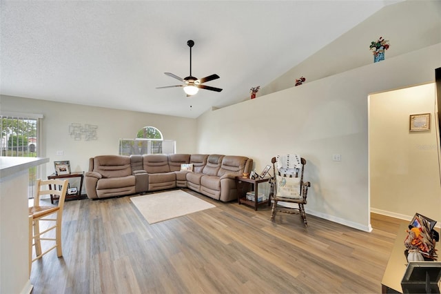 living room with ceiling fan, high vaulted ceiling, and light hardwood / wood-style floors