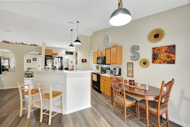 kitchen with light hardwood / wood-style flooring, a kitchen island, hanging light fixtures, and black appliances