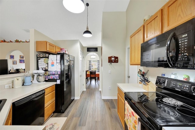 kitchen with pendant lighting, light hardwood / wood-style floors, and black appliances