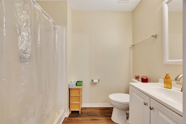 bathroom with hardwood / wood-style floors, vanity, a shower with shower curtain, toilet, and a textured ceiling