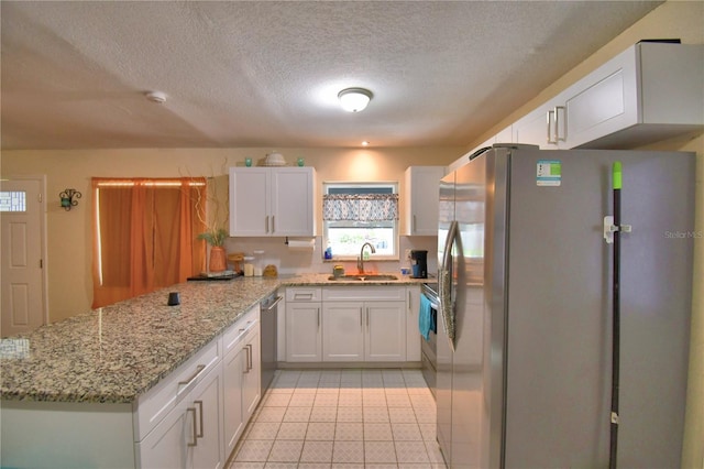 kitchen with light stone countertops, sink, white cabinetry, and stainless steel appliances