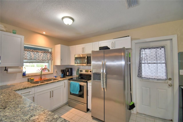 kitchen featuring light stone countertops, appliances with stainless steel finishes, a textured ceiling, sink, and white cabinets