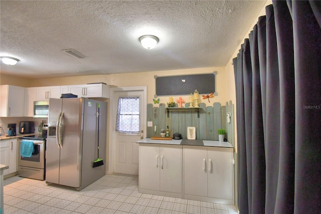 kitchen featuring a textured ceiling, white cabinetry, stainless steel appliances, and light tile patterned floors