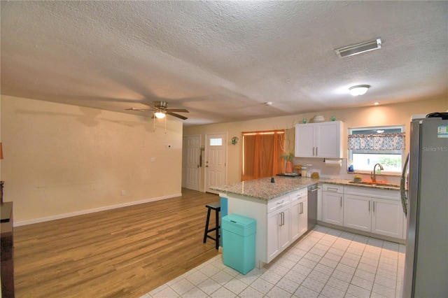 kitchen with white cabinetry, stainless steel appliances, a kitchen breakfast bar, light hardwood / wood-style flooring, and kitchen peninsula