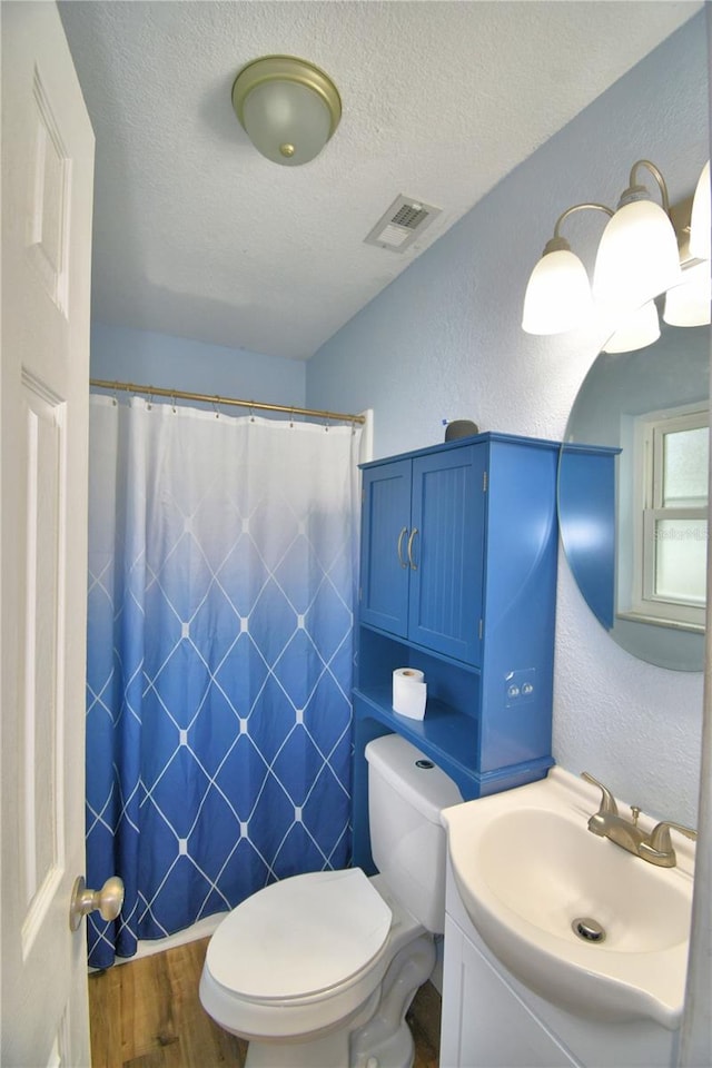 bathroom with vanity, wood-type flooring, a textured ceiling, and toilet