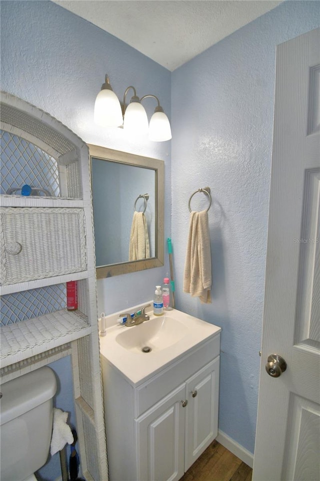 bathroom featuring wood-type flooring, vanity, a textured ceiling, and toilet