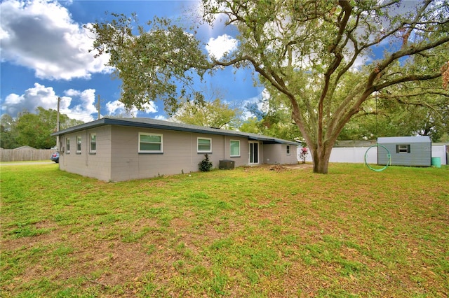 rear view of property with an outdoor structure, a yard, and cooling unit