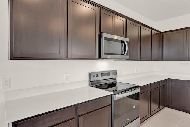 kitchen featuring dark brown cabinets, light tile patterned floors, and appliances with stainless steel finishes