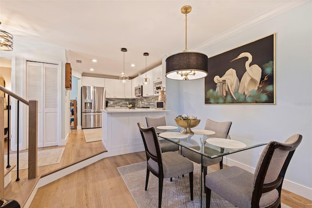 dining space featuring crown molding, a chandelier, and light hardwood / wood-style floors