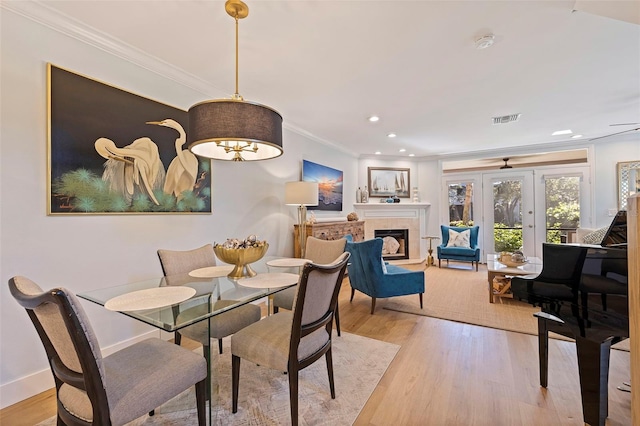 dining room featuring crown molding, baseboards, light wood finished floors, and visible vents
