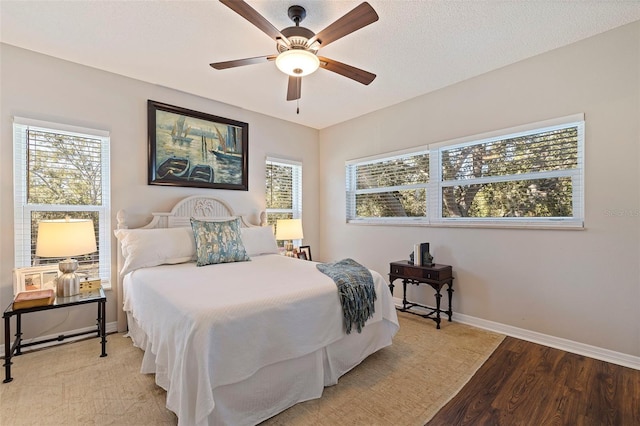 bedroom featuring light wood finished floors, baseboards, a textured ceiling, and a ceiling fan