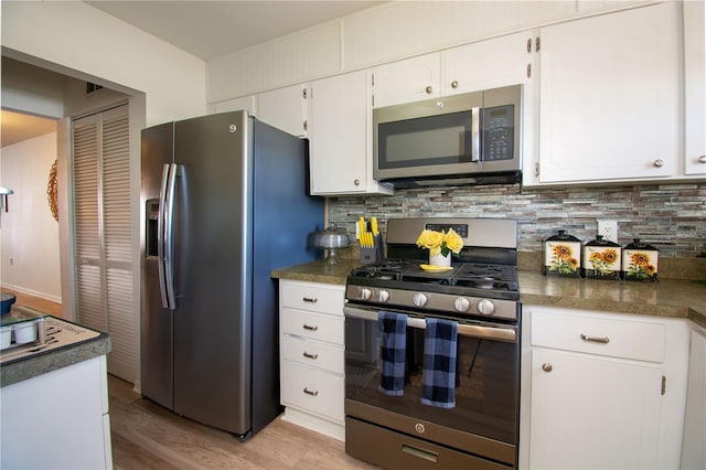 kitchen with backsplash, white cabinetry, stainless steel appliances, and light hardwood / wood-style floors