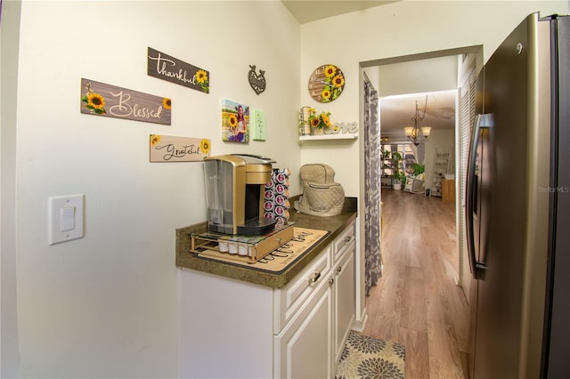 kitchen featuring a notable chandelier, white cabinetry, light wood-type flooring, and stainless steel refrigerator