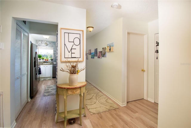 corridor featuring a textured ceiling and light hardwood / wood-style flooring