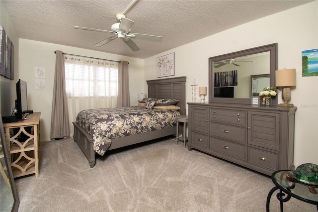 bedroom with ceiling fan, light carpet, and a textured ceiling