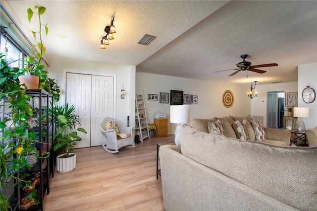 living room with a textured ceiling, light hardwood / wood-style flooring, and ceiling fan