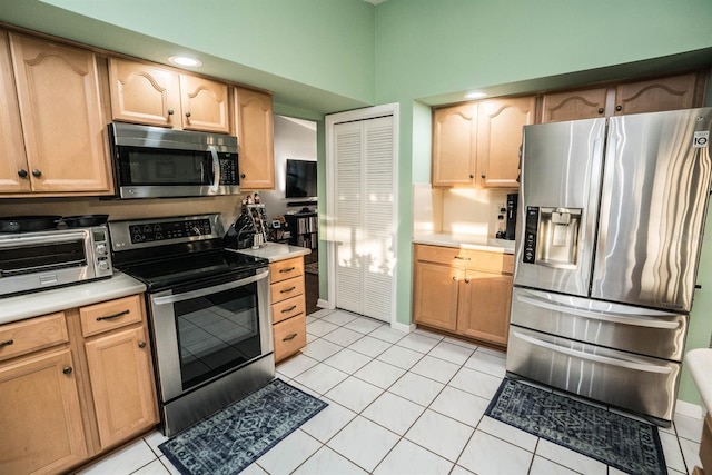 kitchen featuring a towering ceiling, light tile patterned floors, and appliances with stainless steel finishes