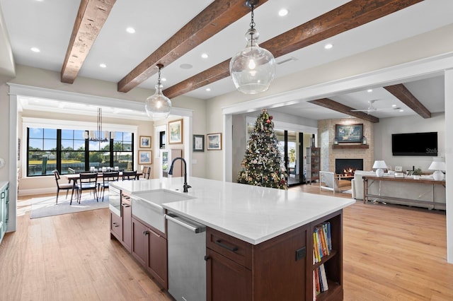 kitchen with hanging light fixtures, dishwasher, and a center island with sink